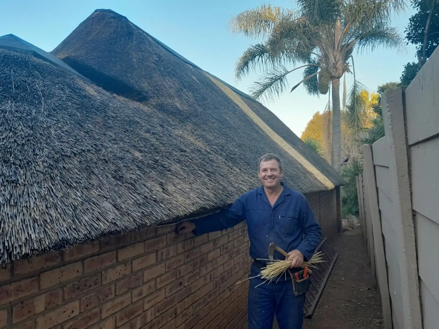 Thatcher standing beside a freshly completed thatch roof in Waterkloof